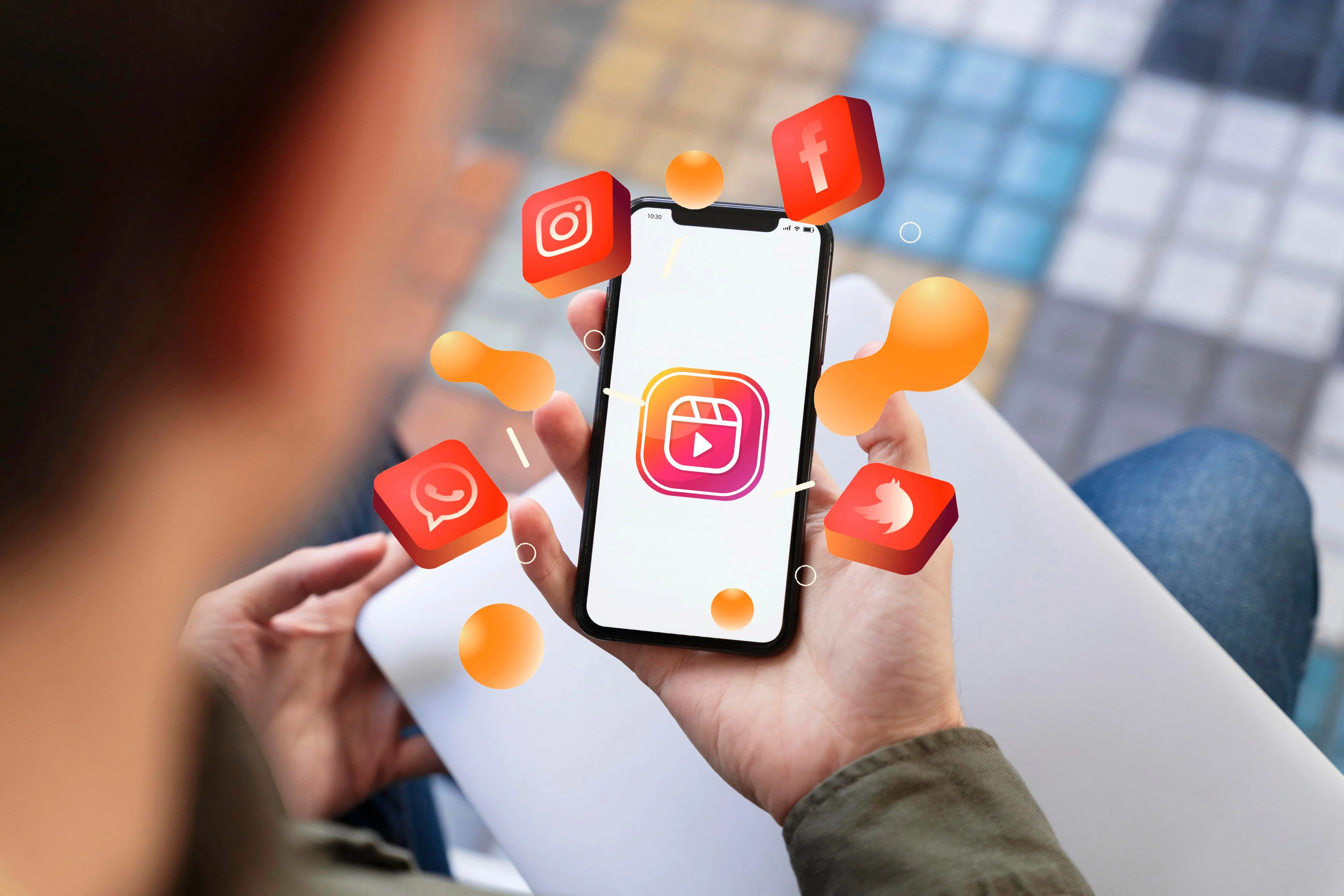 Person holding a smartphone with social media icons floating around the screen.
